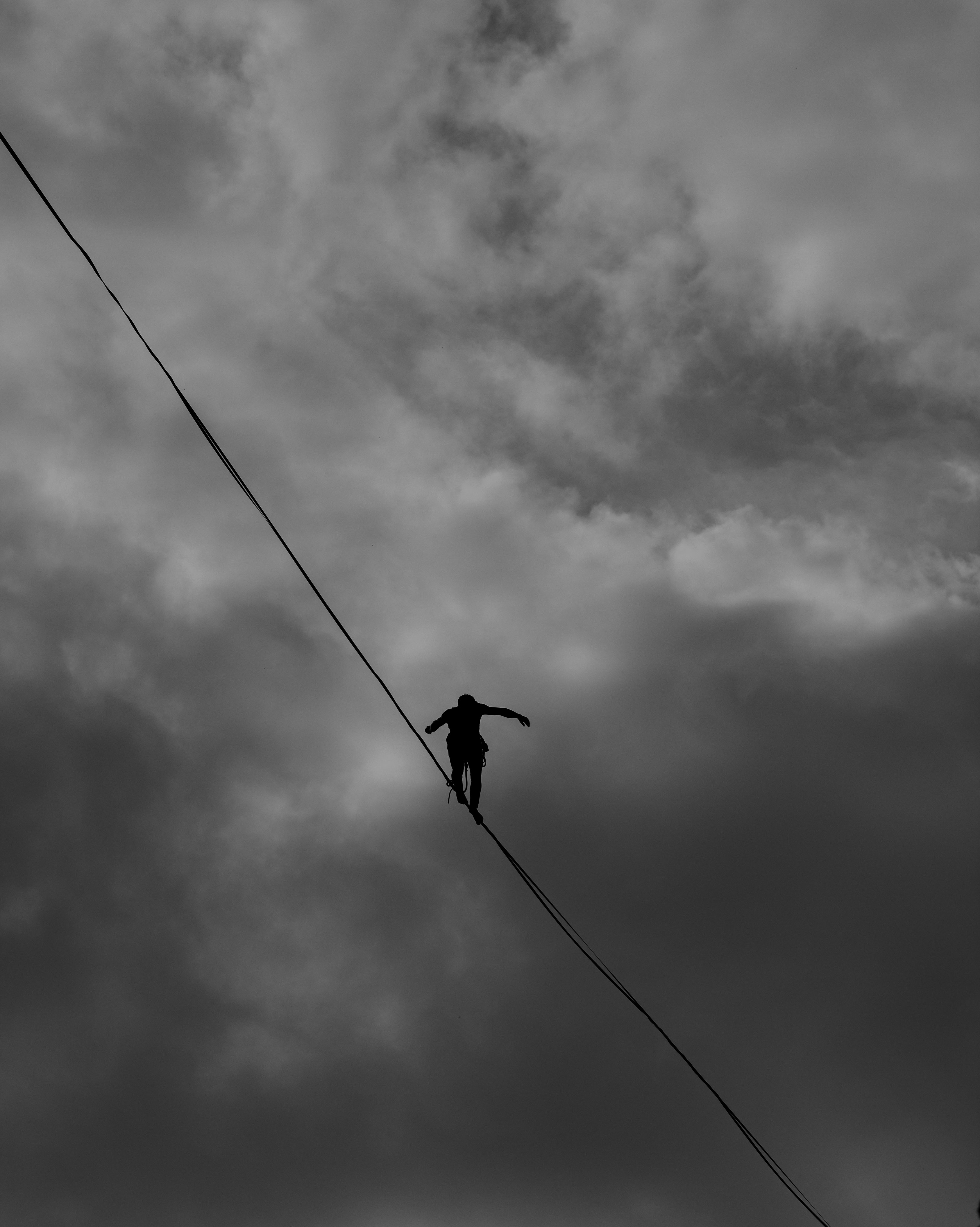 low-angle-photo-grayscale-of-person-tightrope-walking